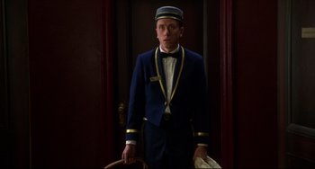 Movie still from “Four Rooms” (1995), directed by Robert Rodriguez – A man in a blue suit standing in front of a door; Medium shot, Low angle