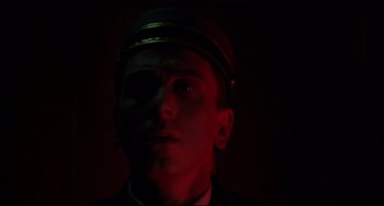 Movie still from “Four Rooms” (1995), directed by Robert Rodriguez – A man wearing a uniform and a hat is in the dark; Close Up shot, Low angle