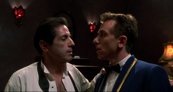 Movie still from “Four Rooms” (1995), directed by Robert Rodriguez – Two men in suits and ties one of which has his mouth on the other's cheek; Close Up shot, Low angle