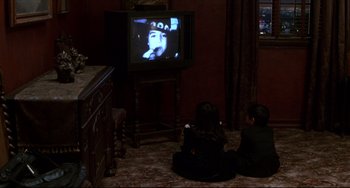 Movie still from “Four Rooms” (1995), directed by Robert Rodriguez – Two people sitting in front of a television; Wide shot, High angle