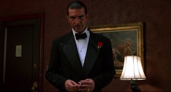 Movie still from “Four Rooms” (1995), directed by Robert Rodriguez – A man in a tuxedo standing in front of a painting; Medium shot, Low angle