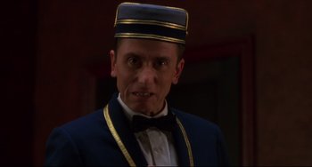Movie still from “Four Rooms” (1995), directed by Robert Rodriguez – A person wearing a hat and a bow tie; Close Up shot, Low angle