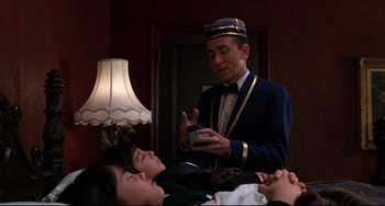 Movie still from “Four Rooms” (1995), directed by Robert Rodriguez – A man holding a cell phone next to two women; Medium shot, Low angle