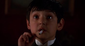 Movie still from “Four Rooms” (1995), directed by Robert Rodriguez – A young boy is smoking a cigarette while wearing a suit; Close Up shot, High angle