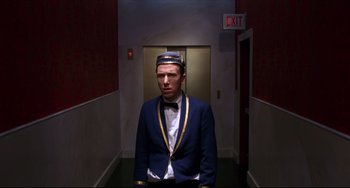 Movie still from “Four Rooms” (1995), directed by Robert Rodriguez – A man in a suit and tie standing in a hallway; Medium shot, Low angle