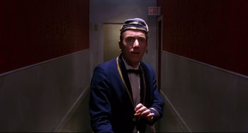 Movie still from “Four Rooms” (1995), directed by Robert Rodriguez – A man in a suit and hat standing in a hallway; Medium shot, Low angle