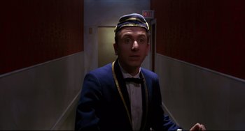 Movie still from “Four Rooms” (1995), directed by Robert Rodriguez – A man in a suit and tie standing in a hallway; Close Up shot, Low angle
