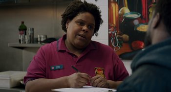 Movie still from “The Upside” (2017), directed by Neil Burger – A person sitting at a table writing on a piece of paper; Close Up shot, Over the shoulder angle