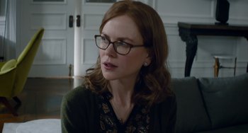 Movie still from “The Upside” (2017), directed by Neil Burger – A person wearing glasses sitting on a couch; Close Up shot, Over the shoulder angle