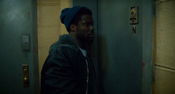 Movie still from “The Upside” (2017), directed by Neil Burger – A man in a blue hat and a black jacket; Medium shot, High angle