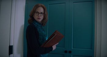 Movie still from “The Upside” (2017), directed by Neil Burger – A woman holding a book in front of two doors; Medium shot, Over the shoulder angle