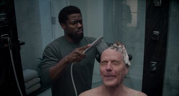 Movie still from “The Upside” (2017), directed by Neil Burger – A man getting his hair brushed by another man in a bathroom; Medium shot, Over the shoulder angle