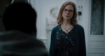 Movie still from “The Upside” (2017), directed by Neil Burger – A woman wearing glasses standing in front of a statue; Medium shot, Over the shoulder angle
