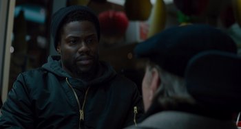 Movie still from “The Upside” (2017), directed by Neil Burger – A man sitting next to another man wearing a hat; Close Up shot, Over the shoulder angle
