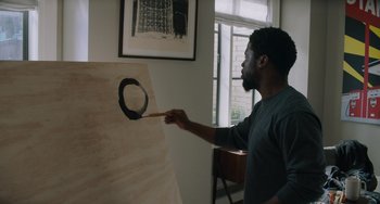 Movie still from “The Upside” (2017), directed by Neil Burger – A man is painting with a brush on a canvas; Medium shot, Over the shoulder angle