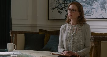 Movie still from “The Upside” (2017), directed by Neil Burger – A woman sitting in front of a table with a book; Medium shot, Low angle
