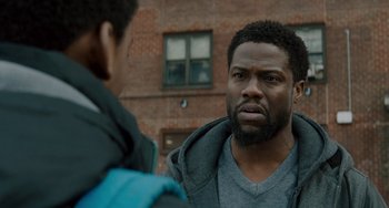 Movie still from “The Upside” (2017), directed by Neil Burger – A man in a gray shirt is looking at a man in a blue jacket; Close Up shot, Over the shoulder angle