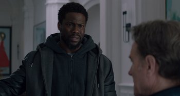 Movie still from “The Upside” (2017), directed by Neil Burger – A man standing next to another man in a room; Medium shot, Over the shoulder angle