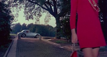 Movie still from “Four Times That Night” (1971), directed by Mario Bava – A woman in a red dress walking down the street; Wide shot, Low angle