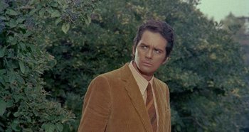 Movie still from “Four Times That Night” (1971), directed by Mario Bava – A man in a suit and tie standing in front of a tree; Medium shot, Low angle