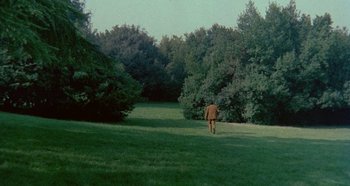 Movie still from “Four Times That Night” (1971), directed by Mario Bava – A man walking through a field with trees in the background; Extreme Wide shot, High angle