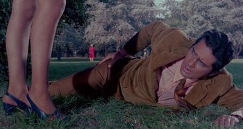 Movie still from “Four Times That Night” (1971), directed by Mario Bava – A man laying in the grass on the ground; Medium shot, High angle