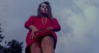 Movie still from “Four Times That Night” (1971), directed by Mario Bava – A woman in a red dress holding a red purse; Medium shot, Low angle