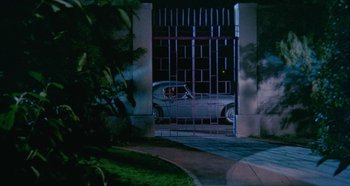 Movie still from “Four Times That Night” (1971), directed by Mario Bava – A car parked in front of a gate at night; Extreme Wide shot, High angle