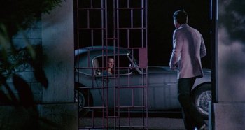 Movie still from “Four Times That Night” (1971), directed by Mario Bava – A man and a woman standing in front of a car; Wide shot, High angle