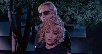 Movie still from “Four Times That Night” (1971), directed by Mario Bava – A man and a woman standing next to each other in front of a tree; Close Up shot, Low angle