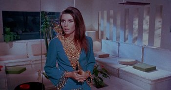 Movie still from “Four Times That Night” (1971), directed by Mario Bava – A woman in a blue and gold dress holding a vase; Medium shot, High angle