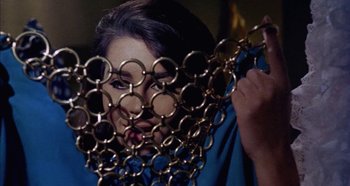 Movie still from “Four Times That Night” (1971), directed by Mario Bava – A woman is holding a bunch of metal rings in front of her face; Close Up shot, Overhead angle