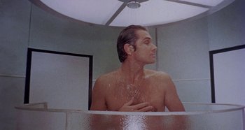Movie still from “Four Times That Night” (1971), directed by Mario Bava – A man taking a shower in a bathroom; Medium shot, Low angle