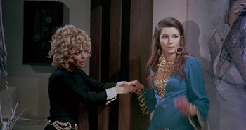 Movie still from “Four Times That Night” (1971), directed by Mario Bava – Two women are shaking hands in front of each other; Medium shot, Over the shoulder angle