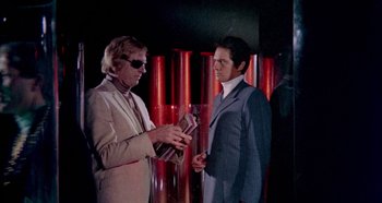 Movie still from “Four Times That Night” (1971), directed by Mario Bava – A man and a woman talking in front of red pipes; Medium shot, Low angle