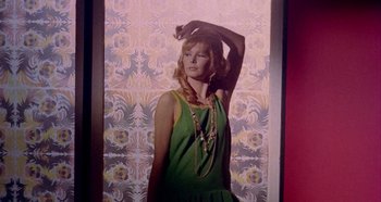 Movie still from “Four Times That Night” (1971), directed by Mario Bava – A woman in a green dress holding up her hair; Medium shot, Low angle