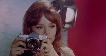 Movie still from “Four Times That Night” (1971), directed by Mario Bava – A woman taking a picture of herself in the mirror; Close Up shot, Low angle