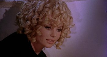 Movie still from “Four Times That Night” (1971), directed by Mario Bava – A person with curly blonde hair; Close Up shot, Low angle