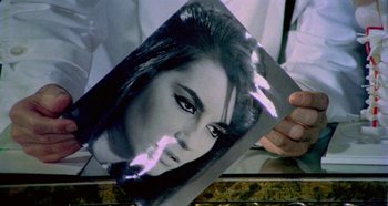 Movie still from “Four Times That Night” (1971), directed by Mario Bava – A person holding a picture of a woman's face; Extreme Close Up shot, High angle