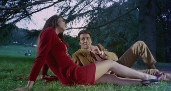 Movie still from “Four Times That Night” (1971), directed by Mario Bava – A man and a woman sitting in the grass; Medium shot, Low angle