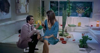 Movie still from “Four Times That Night” (1971), directed by Mario Bava – A man and a woman sitting in a room with wine glasses; Wide shot, High angle