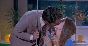 Movie still from “Four Times That Night” (1971), directed by Mario Bava – A man and a woman kissing each other in front of a mirror; Medium shot, High angle