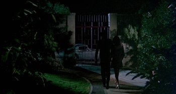 Movie still from “Four Times That Night” (1971), directed by Mario Bava – Two people walking down a sidewalk at night; Extreme Wide shot, High angle