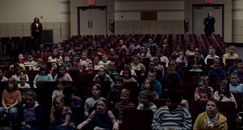 Movie still from “Foxcatcher” (2014), directed by Bennett Miller – A large group of children sitting in a room; Extreme Wide shot, High angle