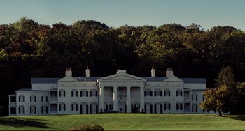 Movie still from “Foxcatcher” (2014), directed by Bennett Miller – A large white building sitting on top of a lush green field; Extreme Wide shot, Low angle
