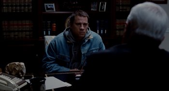 Movie still from “Foxcatcher” (2014), directed by Bennett Miller – A man sitting in front of another man in an office; Medium shot, Over the shoulder angle