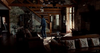Movie still from “Foxcatcher” (2014), directed by Bennett Miller – A man is walking through a living room; Wide shot, High angle