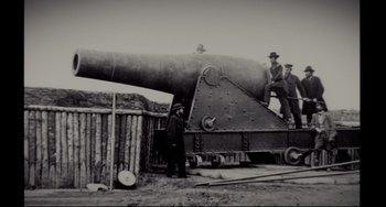 Movie still from “Foxcatcher” (2014), directed by Bennett Miller – Three men standing next to a large cannon; Extreme Wide shot, Low angle