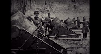 Movie still from “Foxcatcher” (2014), directed by Bennett Miller – A group of men standing next to each other on a train; Medium shot, High angle