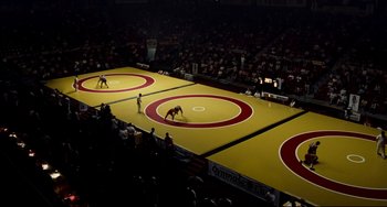 Movie still from “Foxcatcher” (2014), directed by Bennett Miller – Two men are wrestling on a yellow and red wrestling mat; Extreme Wide shot, Overhead angle